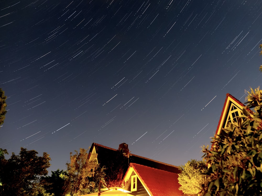 Una casa con un techo rojo bajo un cielo lleno de estrellas