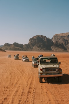 A large convoy of heavy equipment trucks moving along a desert highway in Saudi Arabia under a clear blue sky.