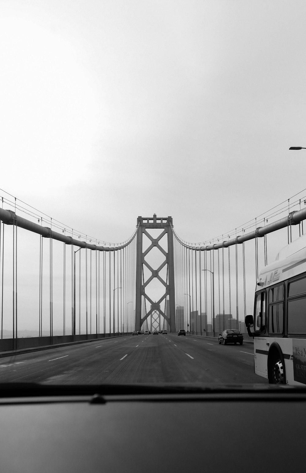a black and white photo of a bridge and a bus
