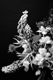 Wide shot of a sleek, asymmetrical floral display blending dark olive greens and soft beige tones in a bright studio setting.