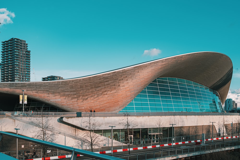 a large building with a curved roof next to a bridge