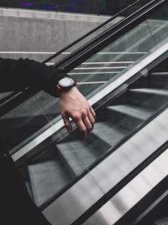 a person with their hand on an escalator