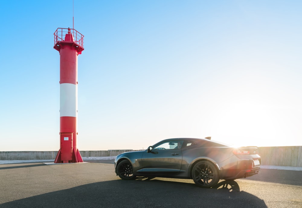 a car parked in front of a red and white light house