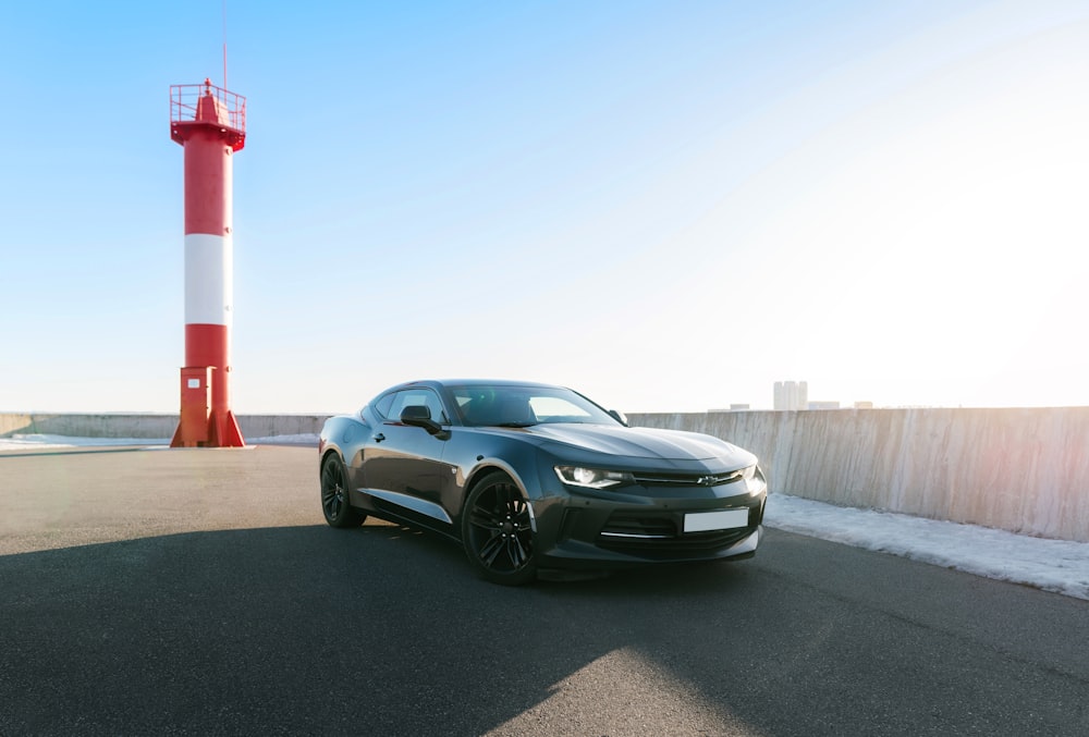 a black car parked in front of a light house