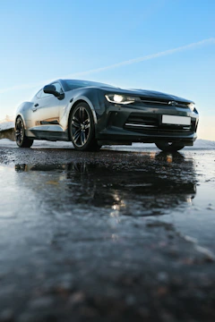 A sleek Japanese sports car parked beside a calm waterfront under a clear sky.