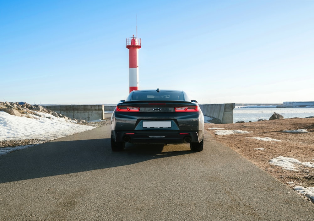 a car parked on the side of a road near a light house
