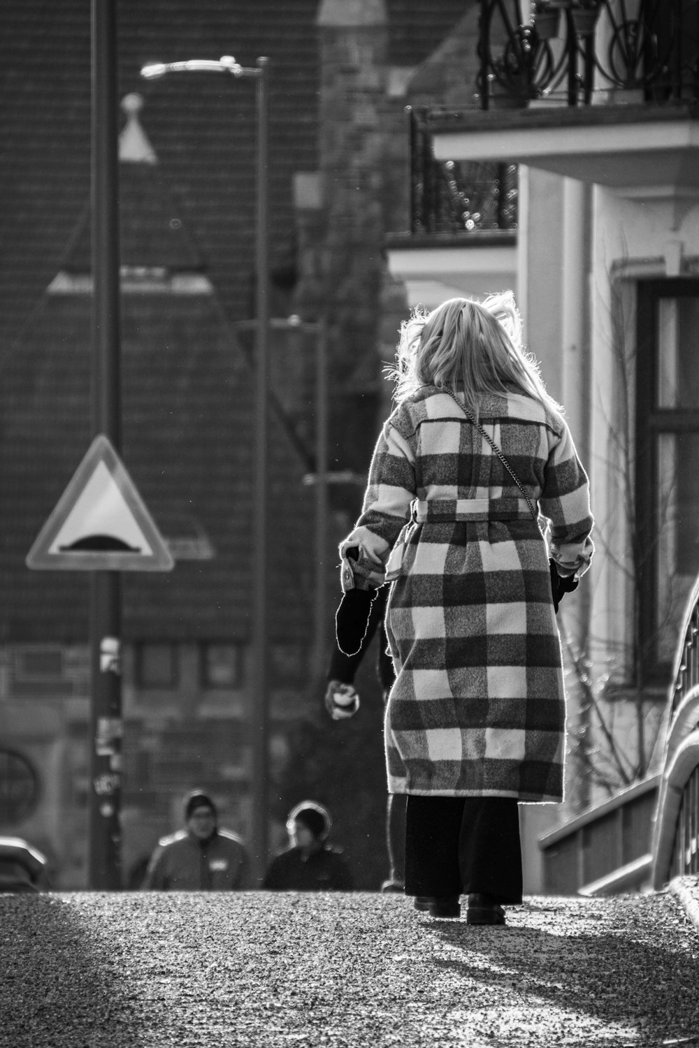 a woman walking down a street holding an umbrella