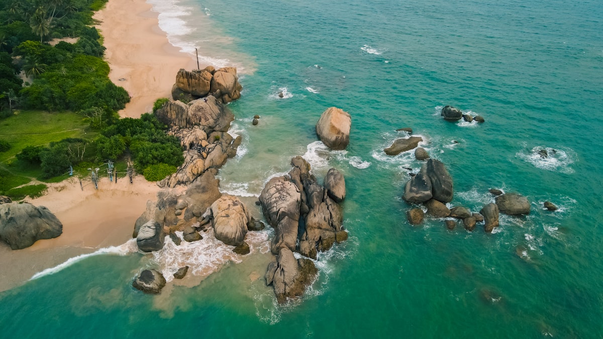 an aerial view of a beach with rocks and water