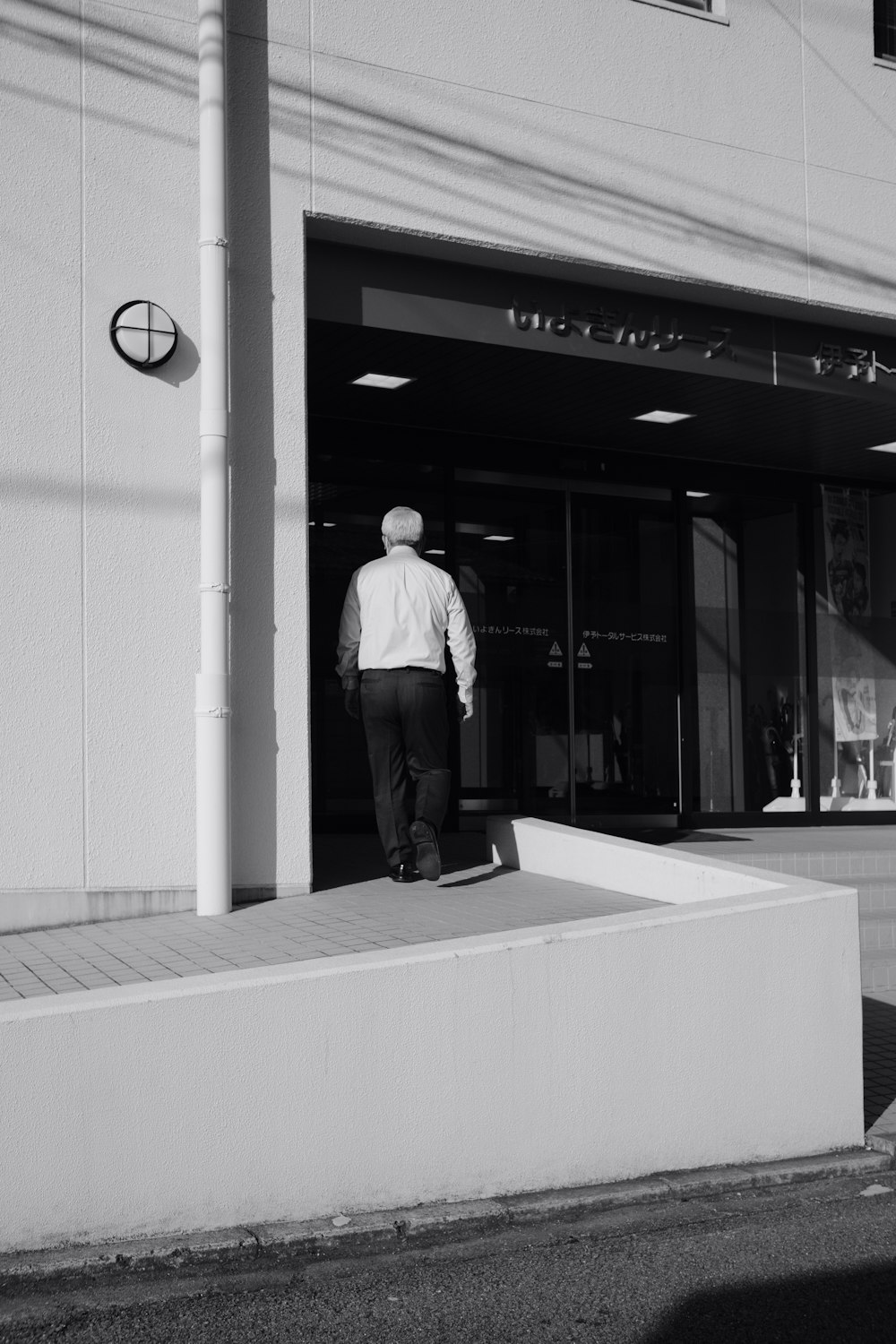 a black and white photo of a man walking out of a building
