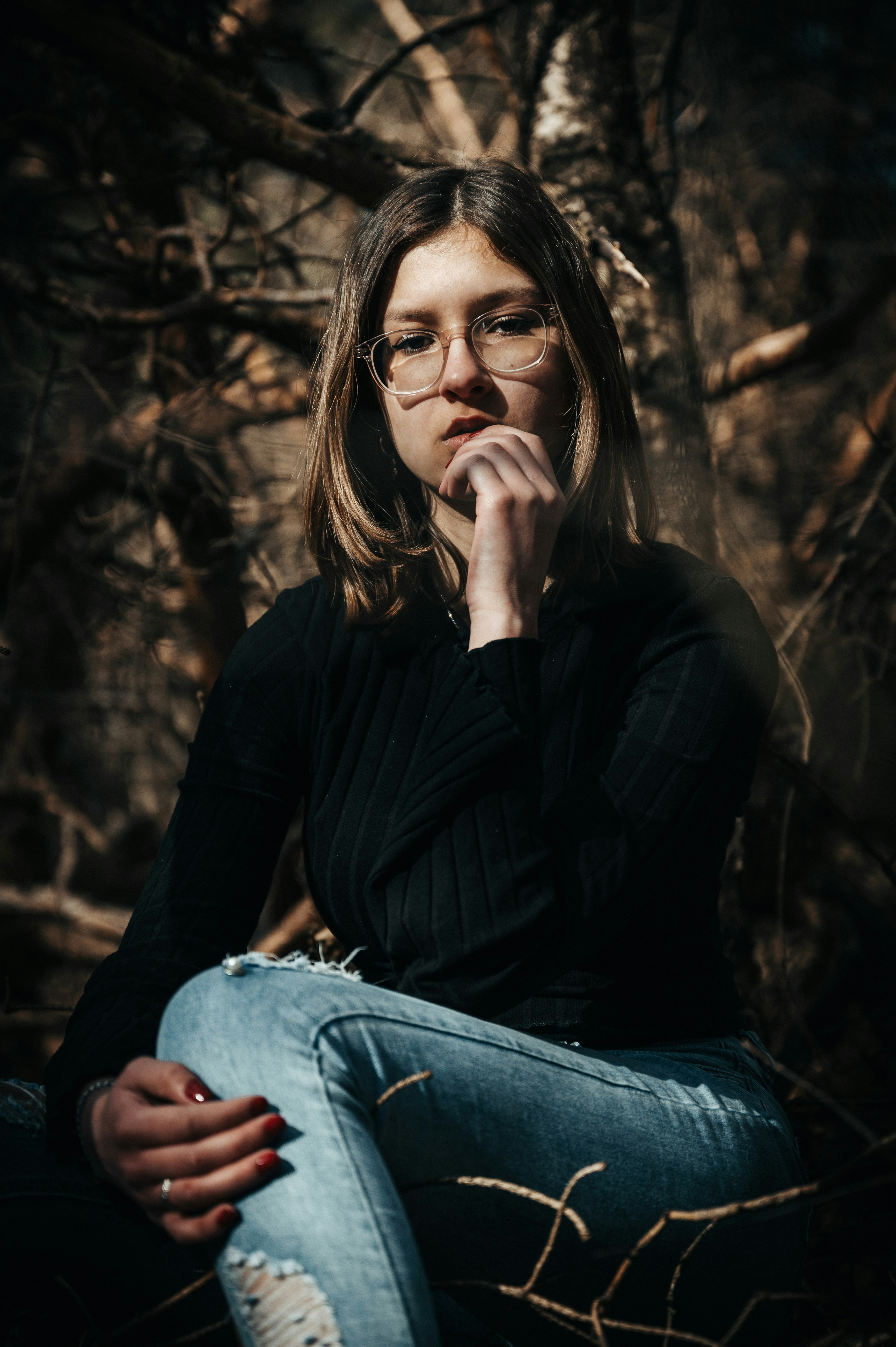 A woman sitting on the ground with her hand on her chin photo – Free ...