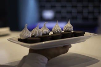 a person is holding a plate with chocolates on it