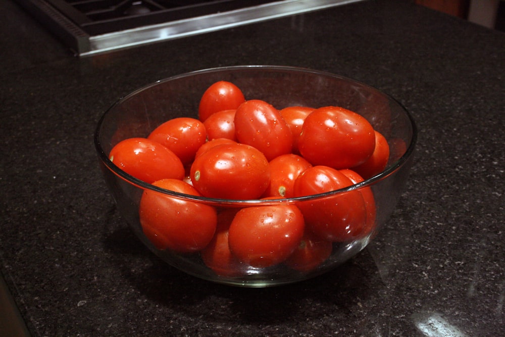 a bowl of tomatoes sitting on a counter top