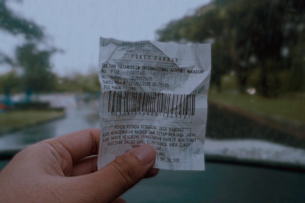 a hand holding a piece of paper with a bar code on it