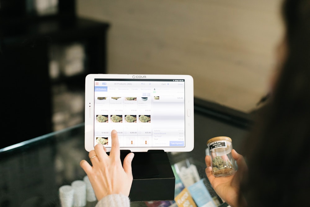 a person holding up a tablet computer in front of a counter