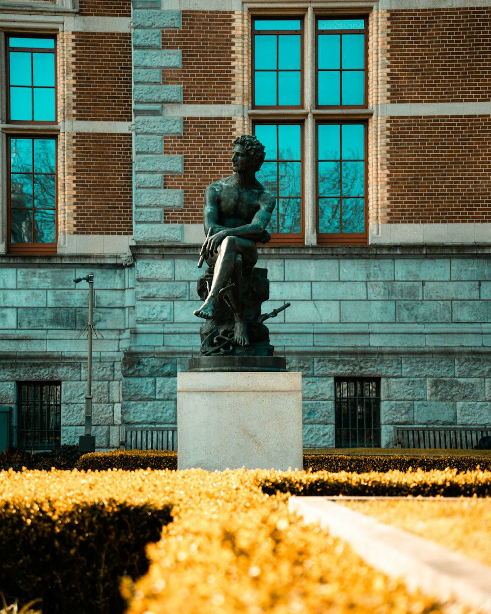 a statue of a man sitting on a bench in front of a building