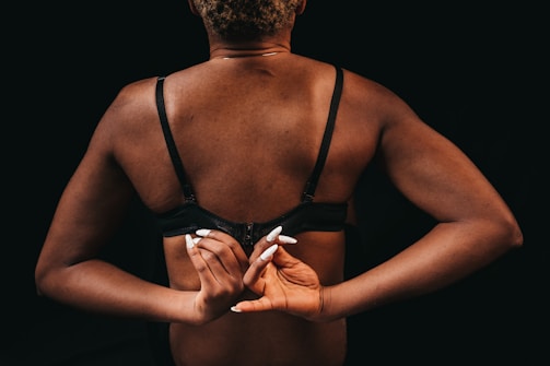 Woman adjusting her bra strap in front of a mirror