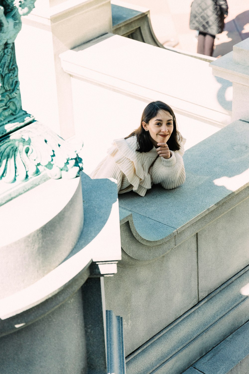 a woman sitting on a ledge in front of a building