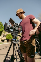 a man standing next to a camera on a tripod