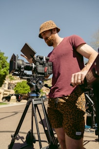 a man standing next to a camera on a tripod