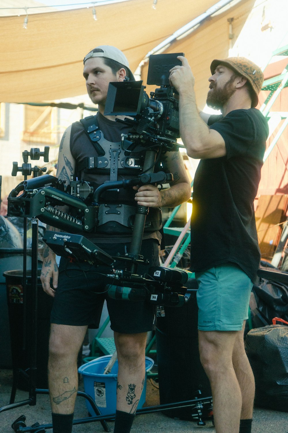 a couple of men standing next to each other in front of a camera