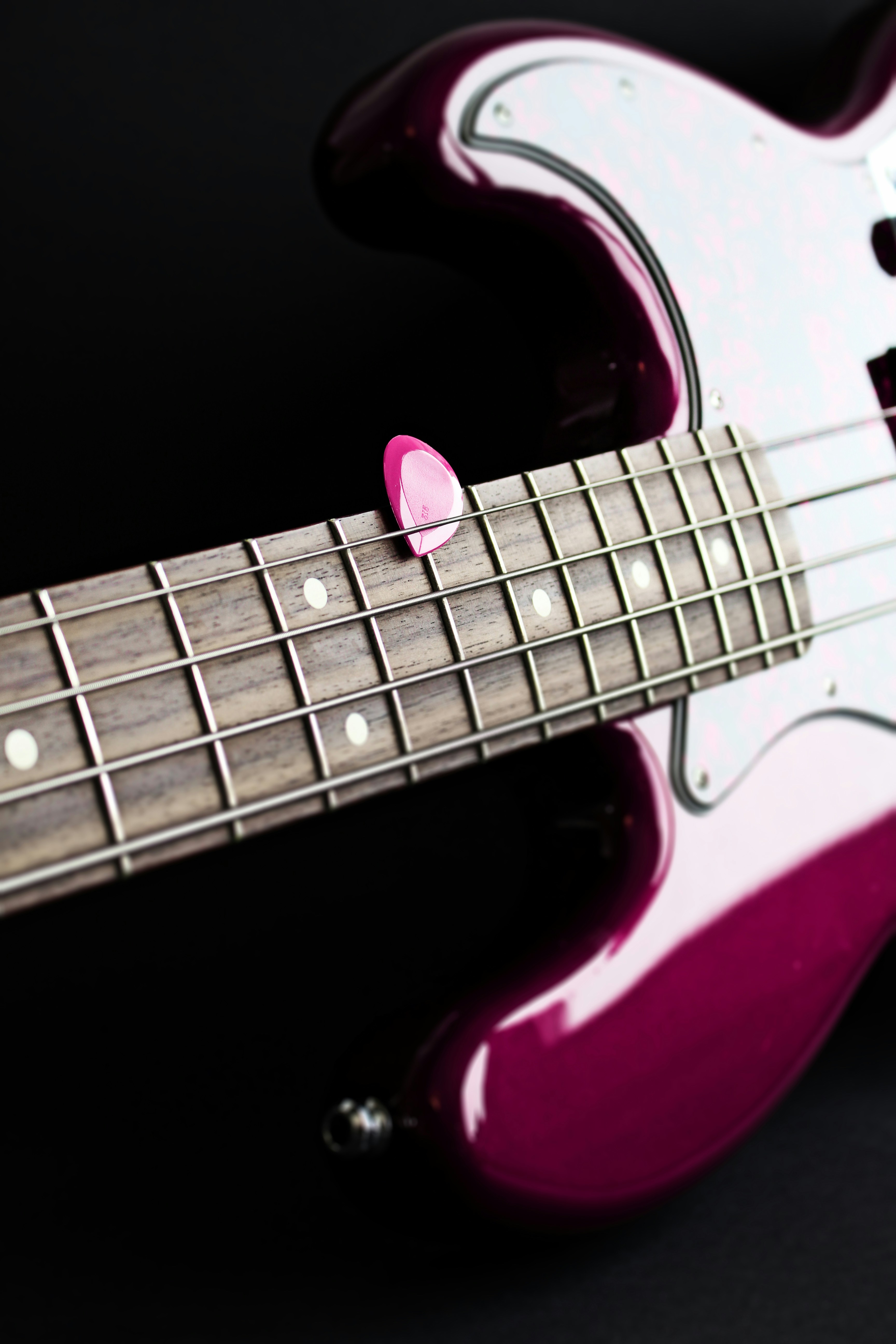 a close up of a pink and white guitar