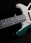 a close up of a green and white bass guitar