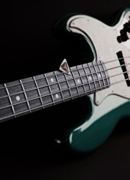a close up of a green and white bass guitar
