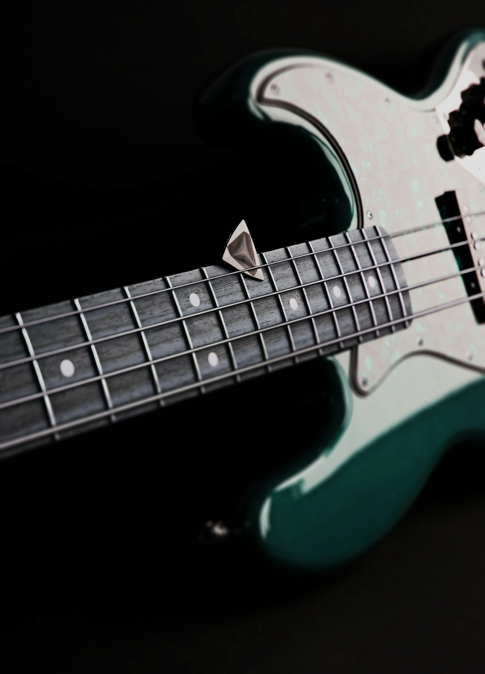 a close up of a green and white bass guitar