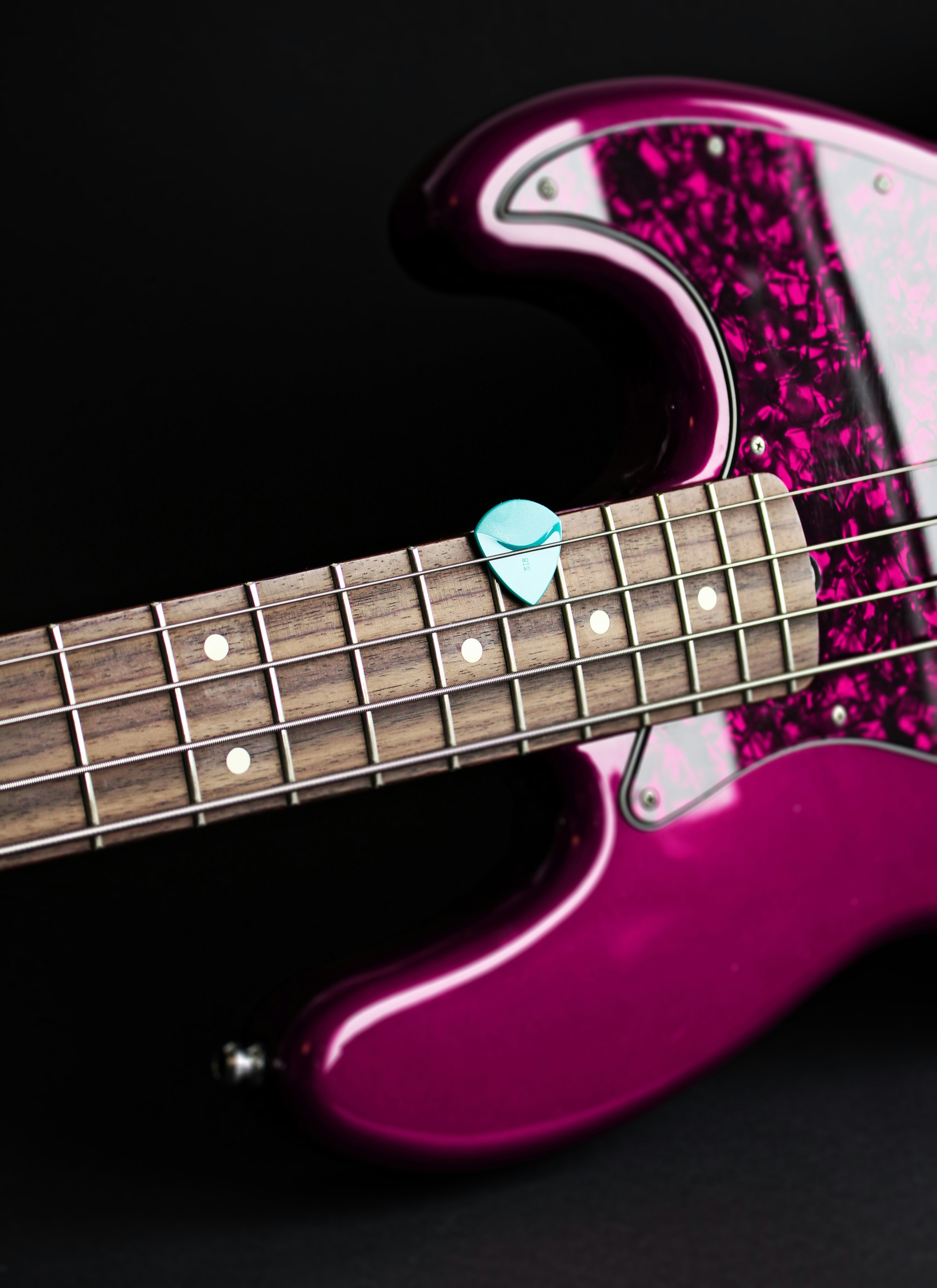 a pink and white guitar with a black background