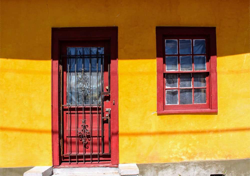 a yellow building with a red door and window