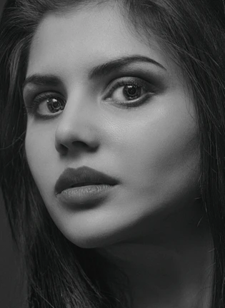 Close-up portrait of a model with sharp cheekbones, bathed in soft monochrome light.