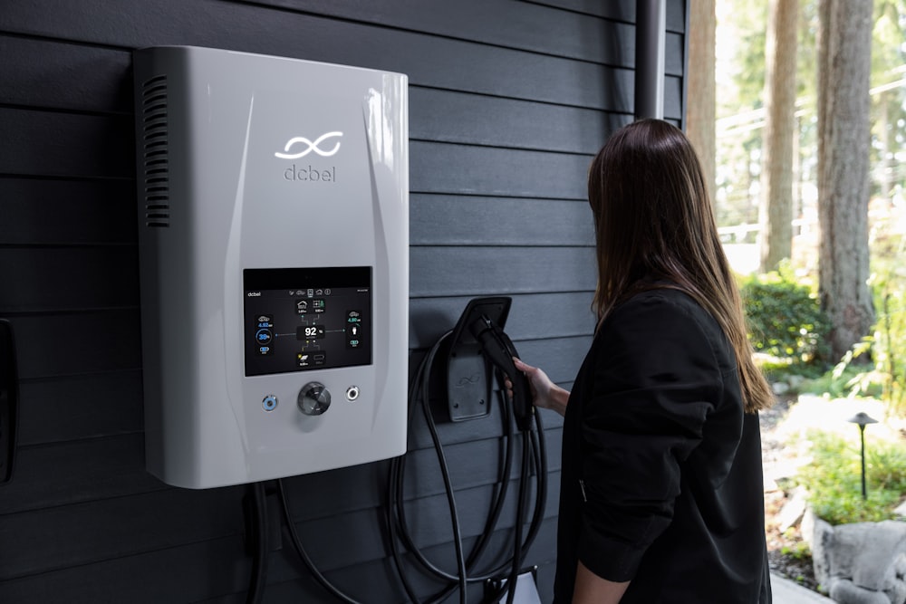 a woman plugging an electric car charger into a wall