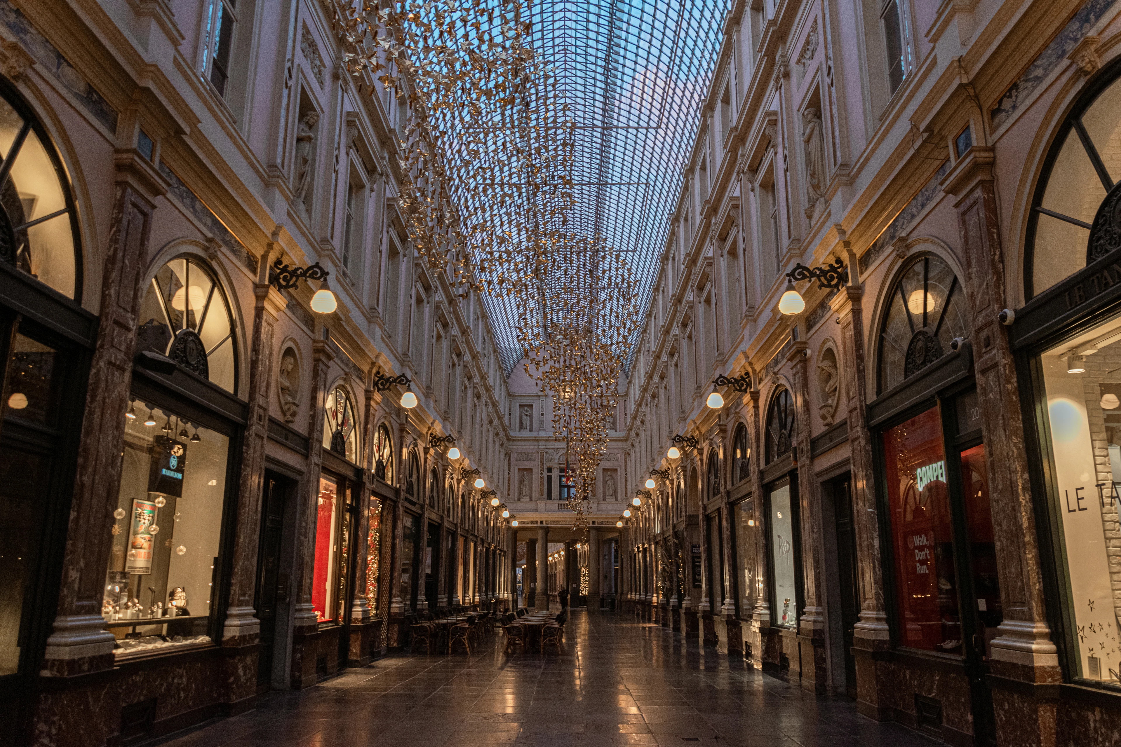 The glass-roofed Galeries Royales Saint-Hubert arcade in Brussels, its shopfronts lined up under hanging chandelier lights