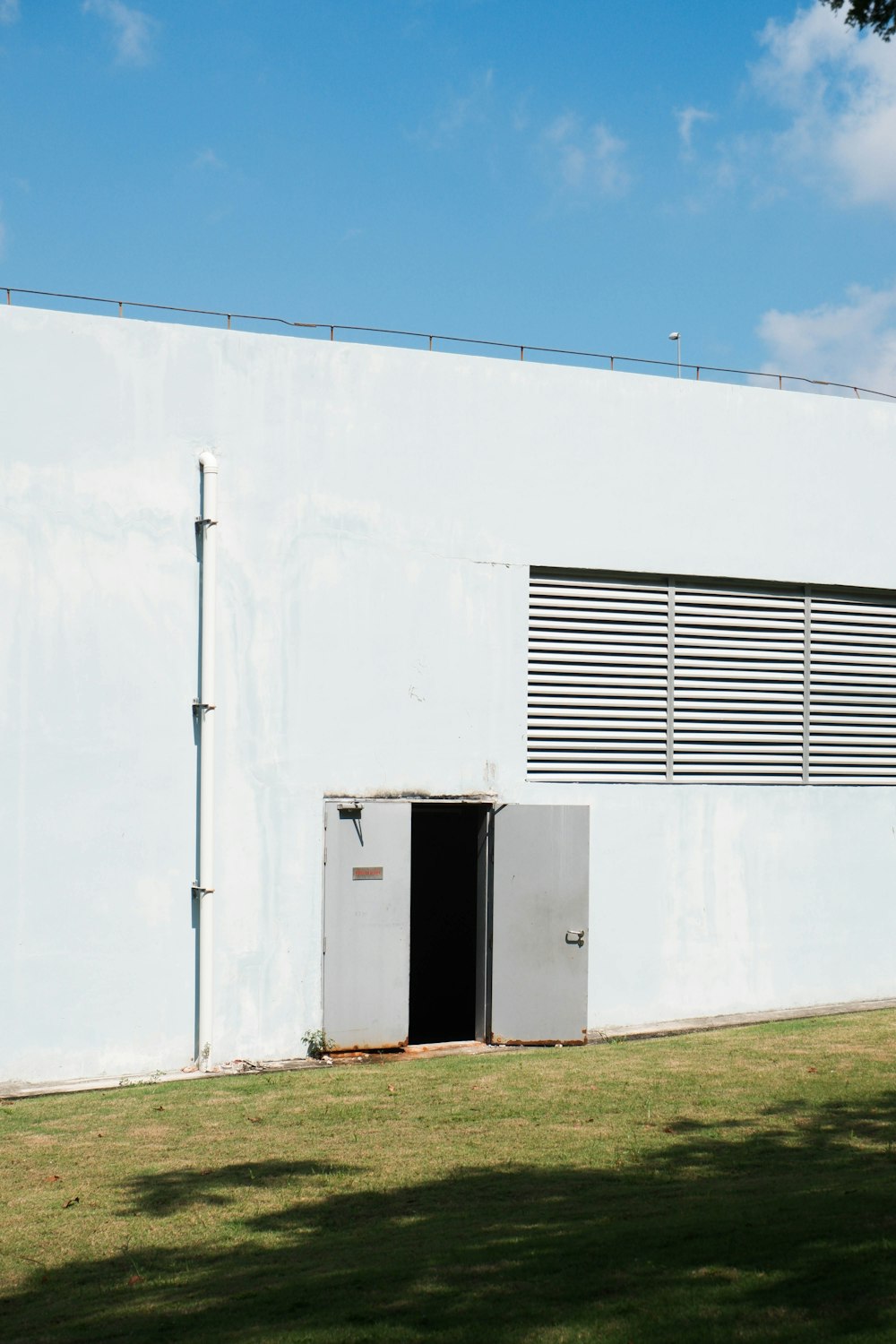 a white building with a black door in the grass