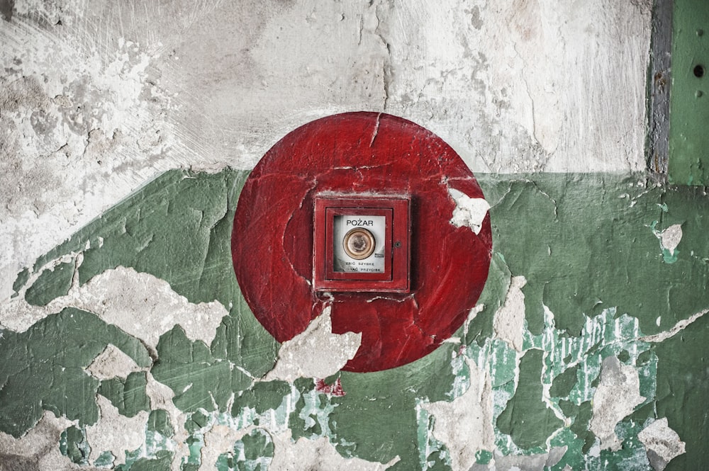 a red button on a green and white wall