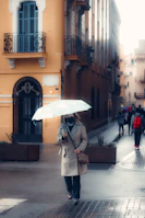A person walking through a city street wearing a sleek Nimbusvale raincoat, umbrella tucked away.