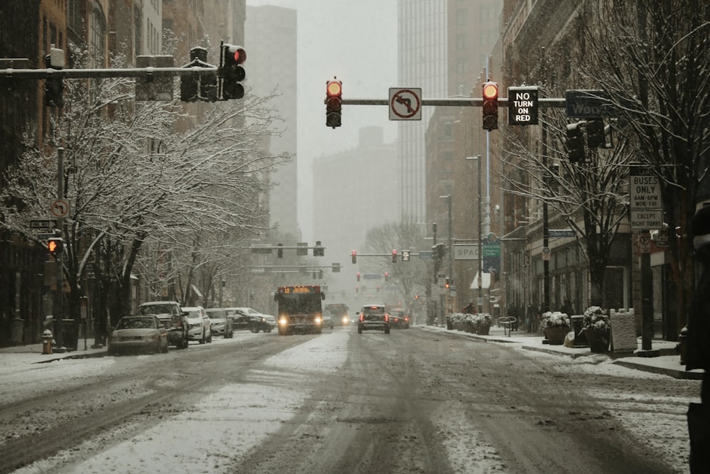 a snowy city street with traffic lights and cars