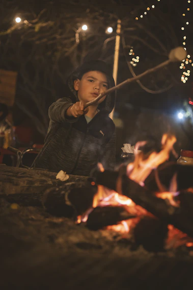 Children laughing together while roasting marshmallows around a cozy campfire at sunset.