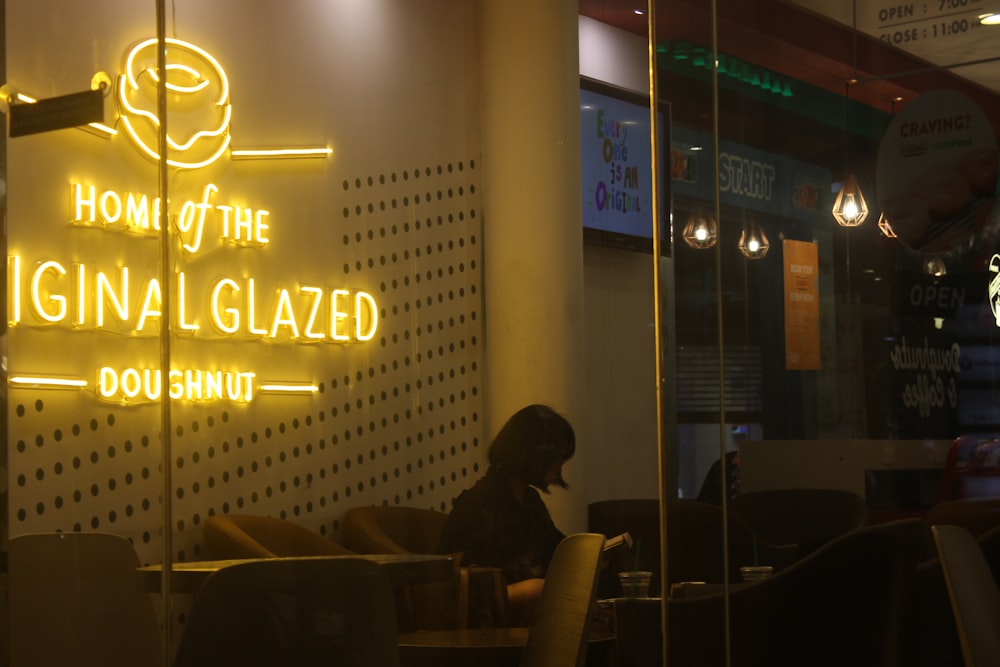 a restaurant with a neon sign that reads, home of the gina glazed dough