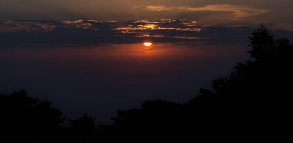 the sun is setting in the sky over the trees