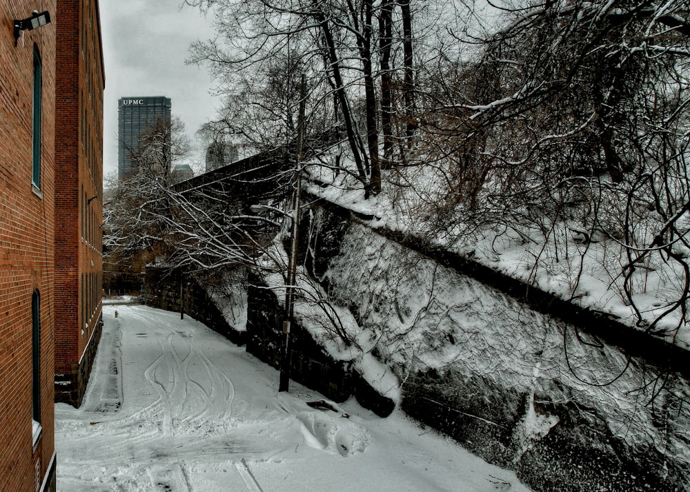 a snow covered street next to a brick building