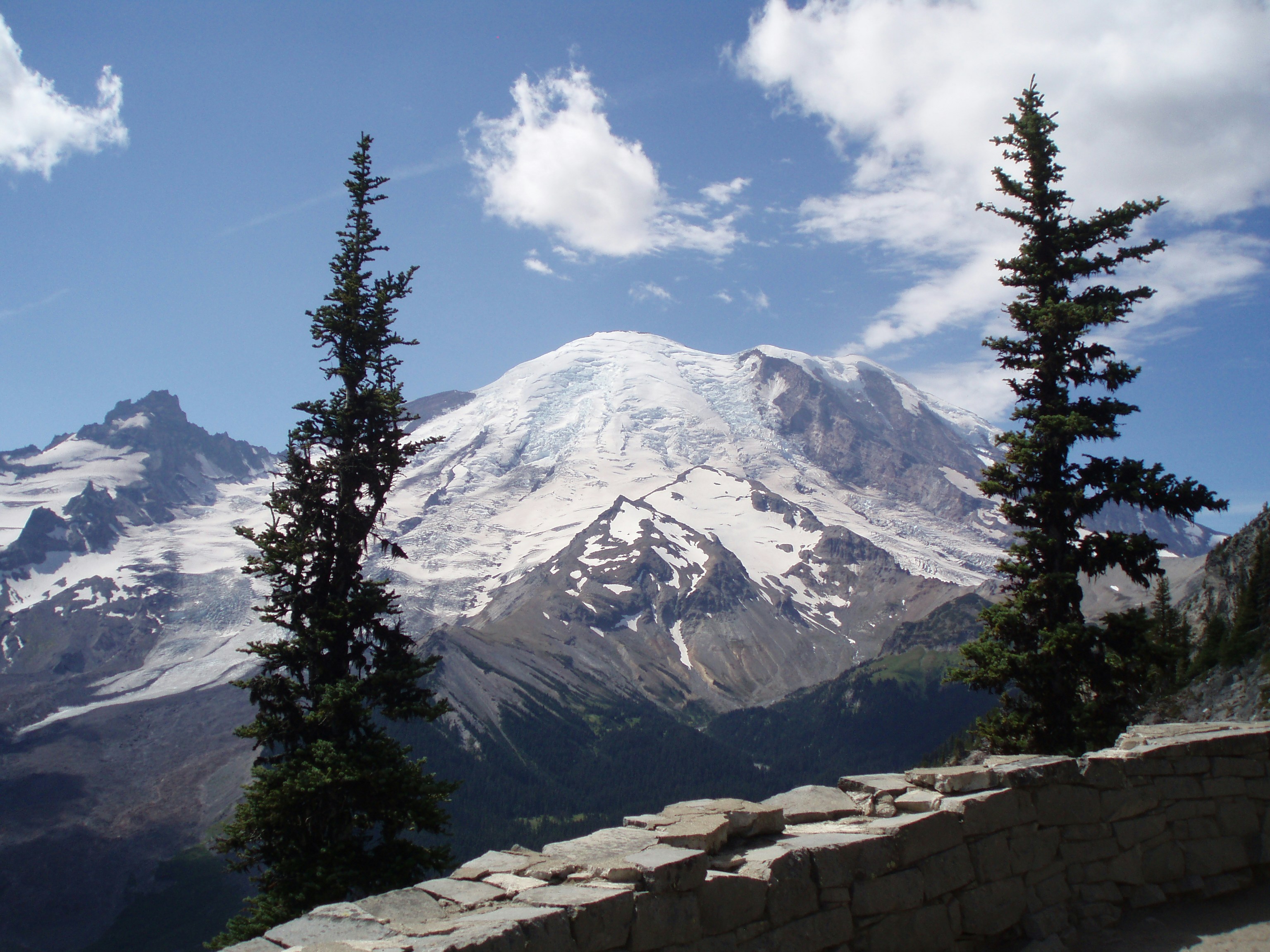 a view of a snow covered mountain from a stone wall