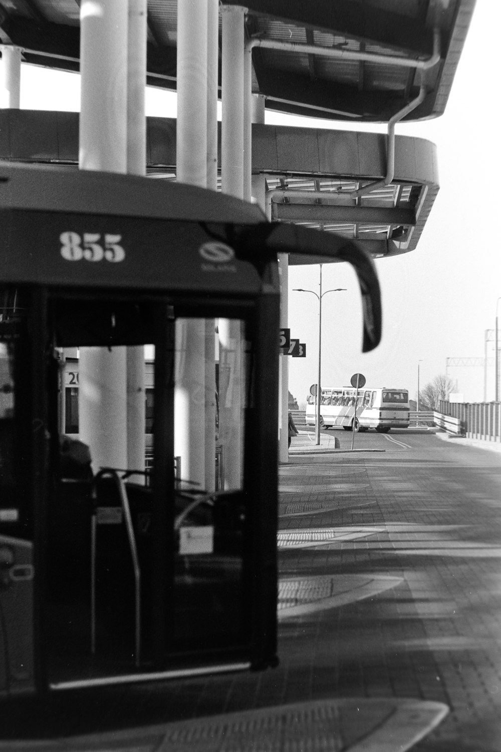 a black and white photo of a bus at a bus stop