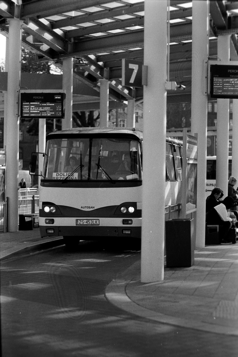a black and white photo of a bus at a train station