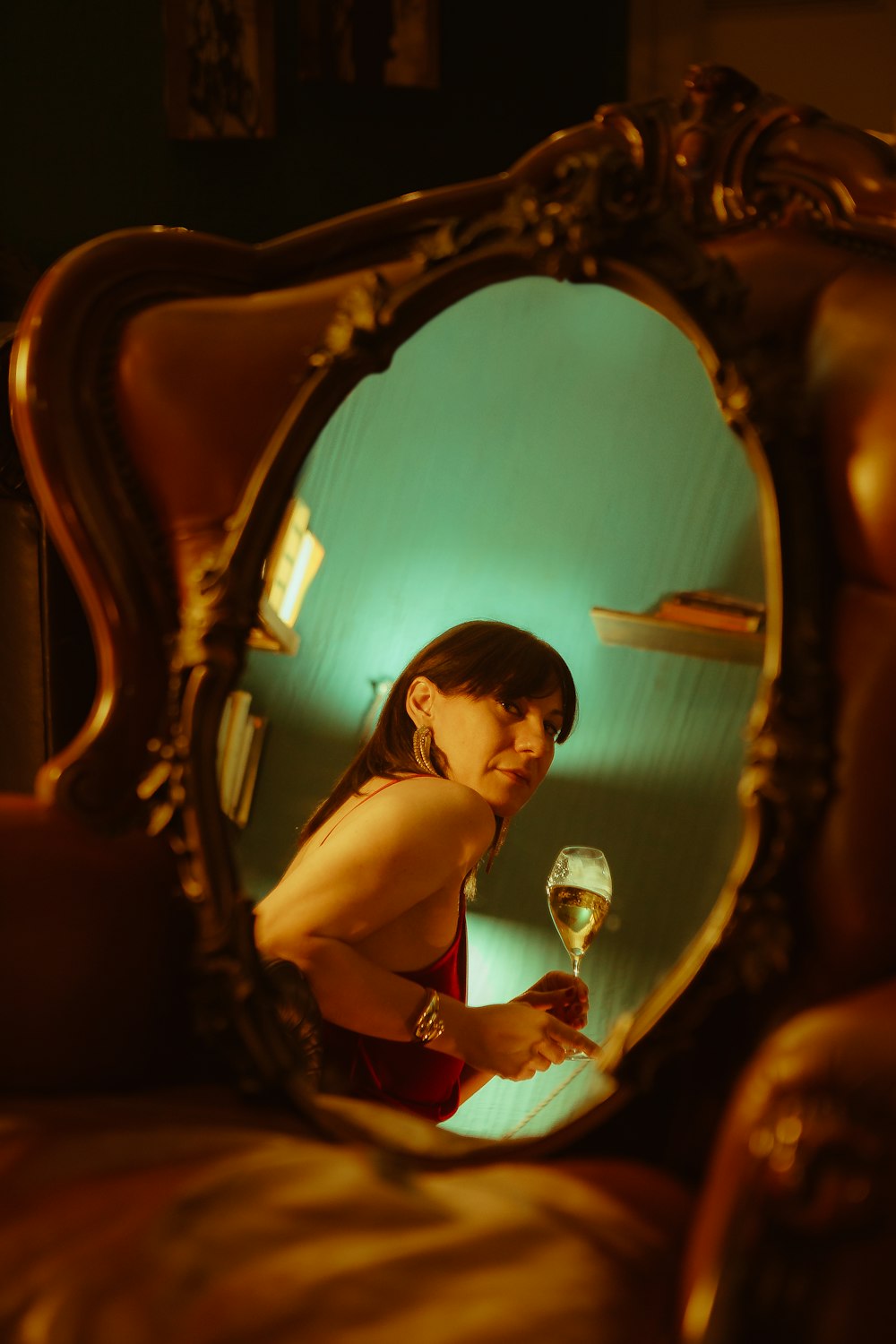 a woman holding a wine glass in front of a mirror