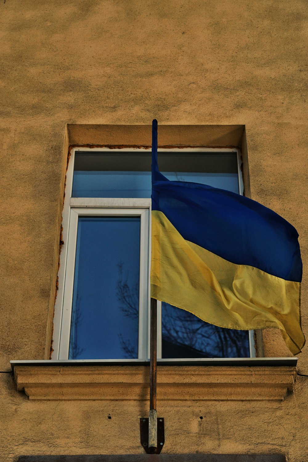 a blue and yellow flag flying from a window