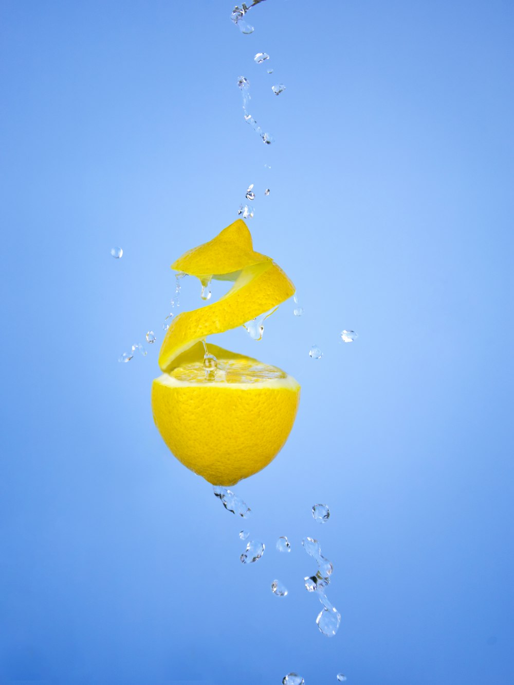 a lemon falling into the water with a blue sky in the background