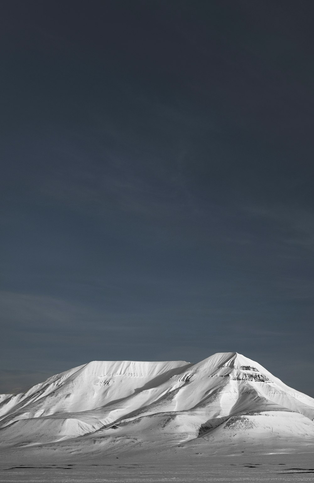 a mountain covered in snow under a cloudy sky