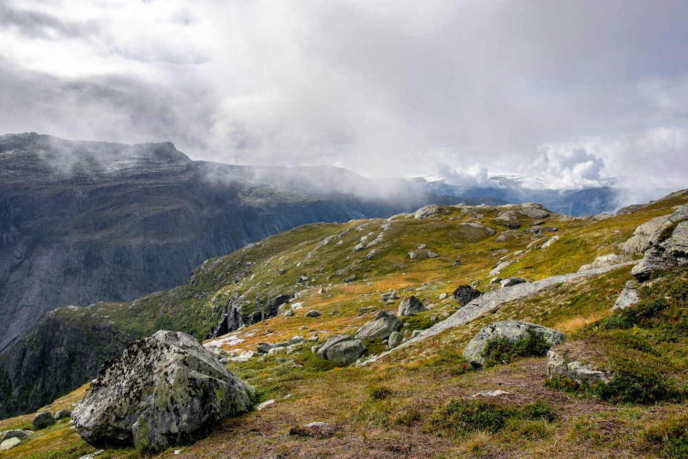 a rocky mountain with grass and rocks in the foreground