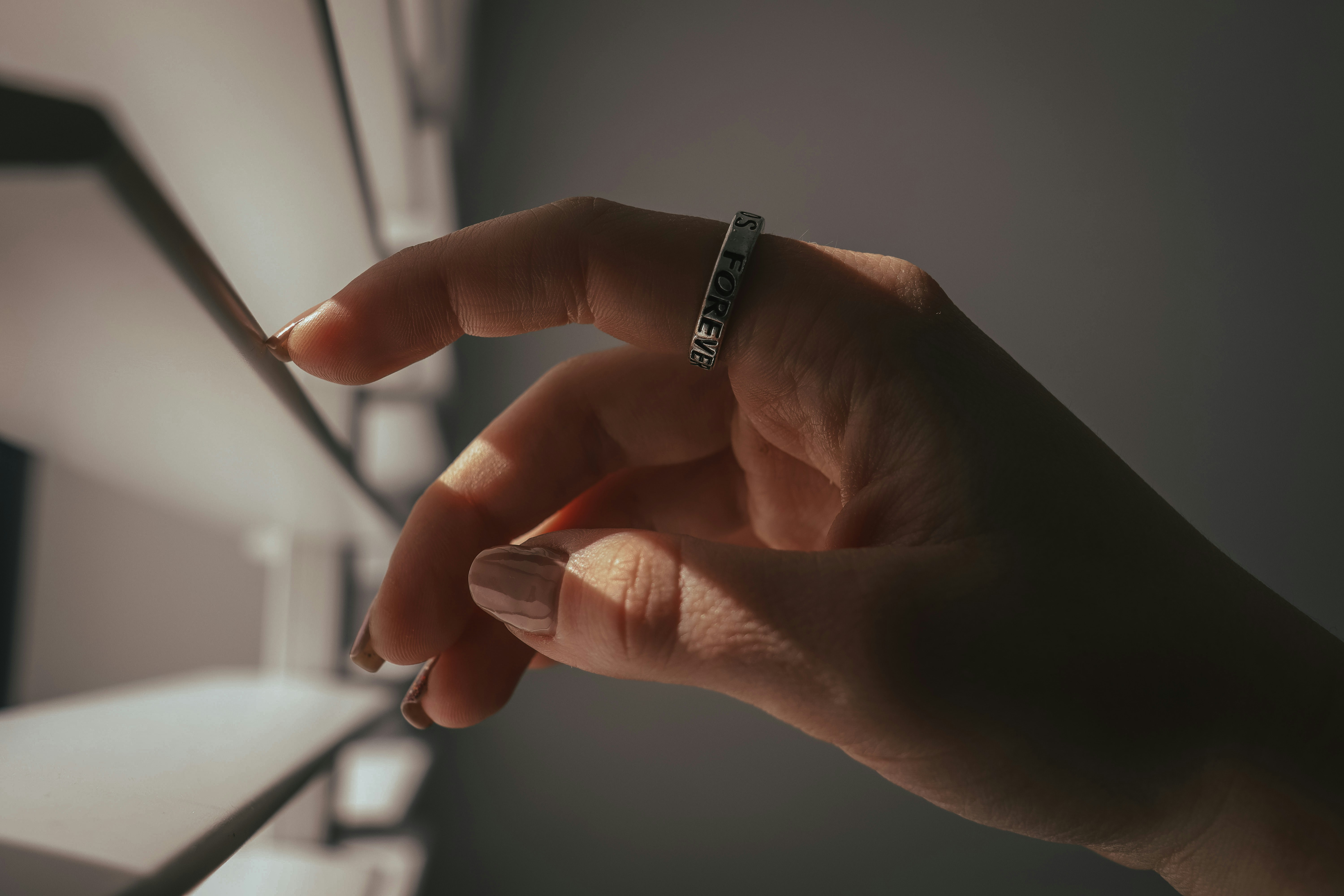  A person's hand wearing a modern, discreet smart ring, subtly interacting with a digital interface, representing seamless integration into daily life and productivity.